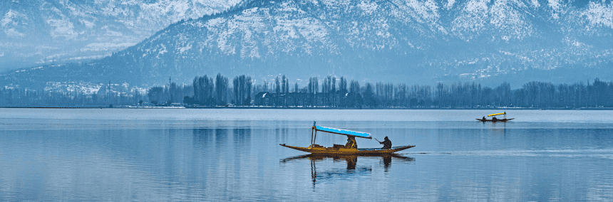 view of a dal lake and a shikara boat in front of snow packed mountains