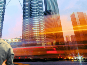 A couple walks side by side, with tall city buildings rising in the background.